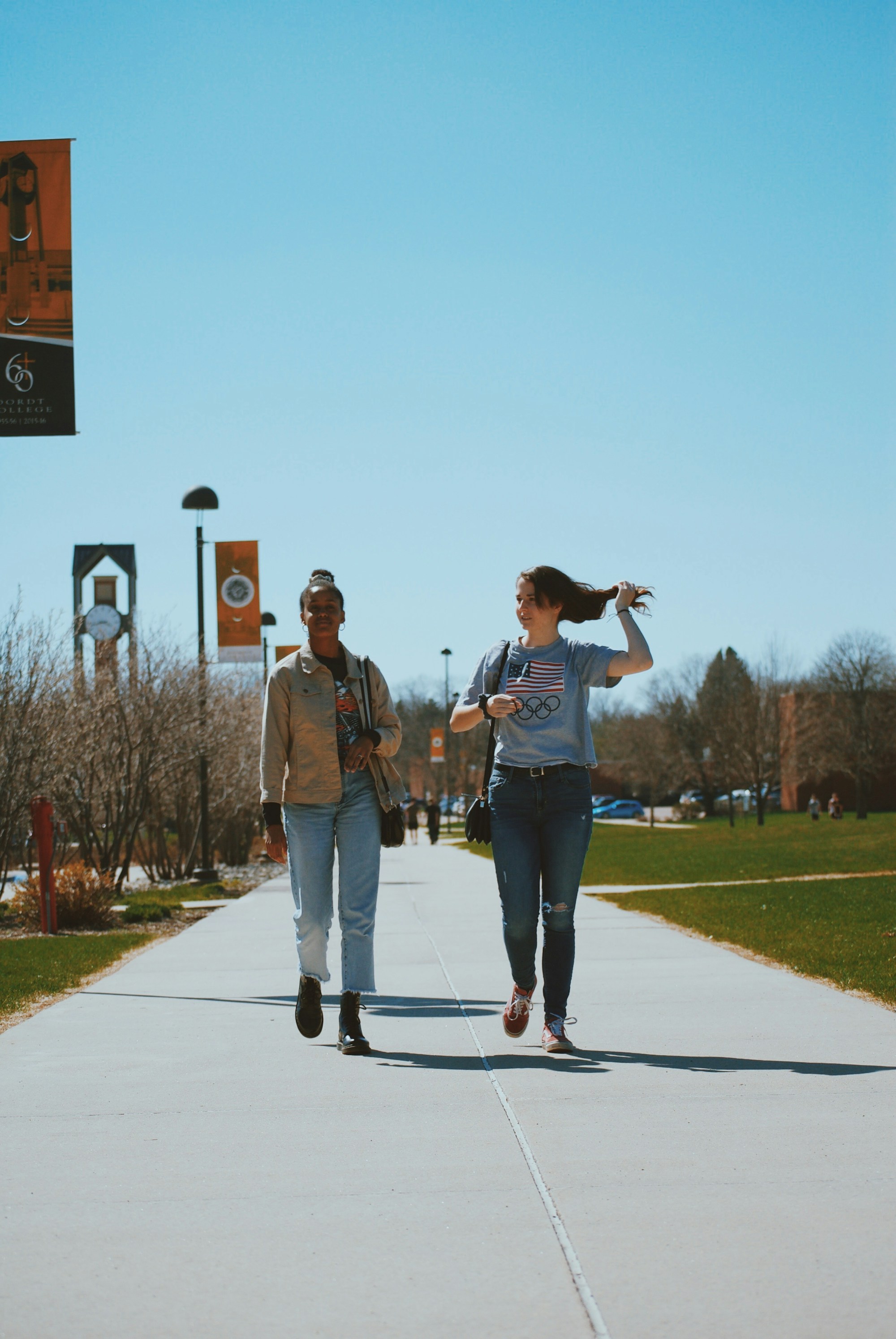Two friends walking together across a sunny college campus