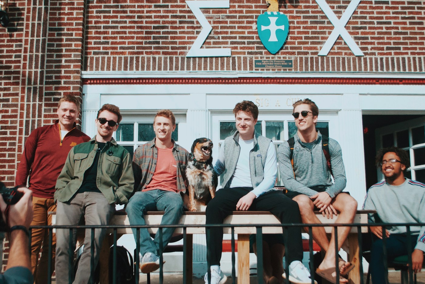 College friends spending a sunny afternoon together outside a campus house